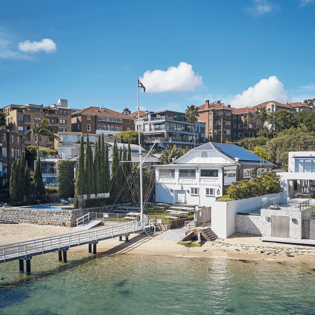 A wide angle image showing the Royal Prince Edward Yacht Club situated on the water including the dock, seating, and a beach area.