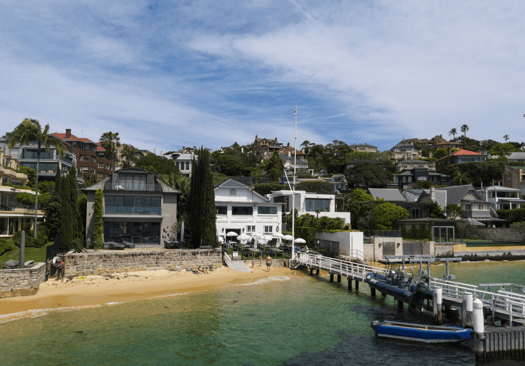 A wide angle image showing the Royal Prince Edward Yacht Club situated on the water including the dock, seating, and a beach area.